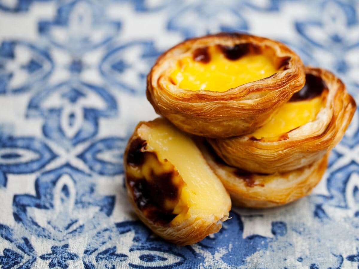 Portugiesische Pastéis de Nata auf blauen Azulejo-Fliesen, Kurs Bem vindo a Portugal!