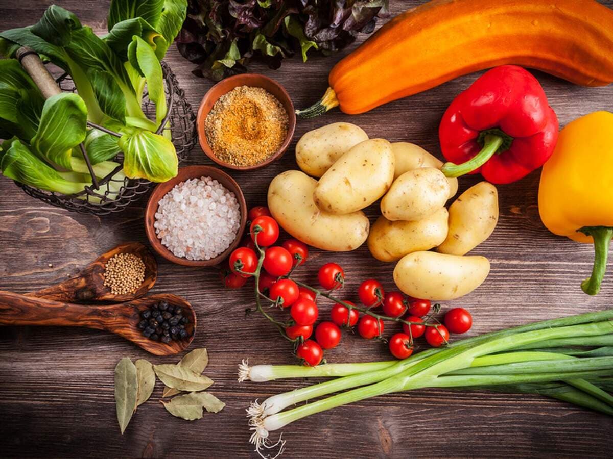 Frisches Gemüse, Kräuter und Gewürze auf dunklem Holz, Kurs Knochenlos kochen