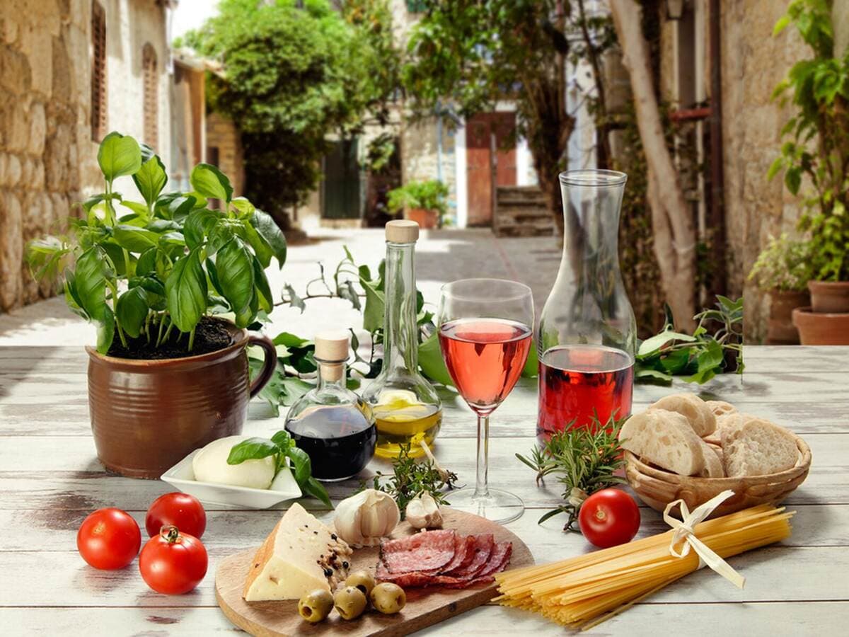 Italienischer Tisch in einer Gasse mit Basilikum, Olivenöl, Wein und Antipasti, Kurs O sole mio